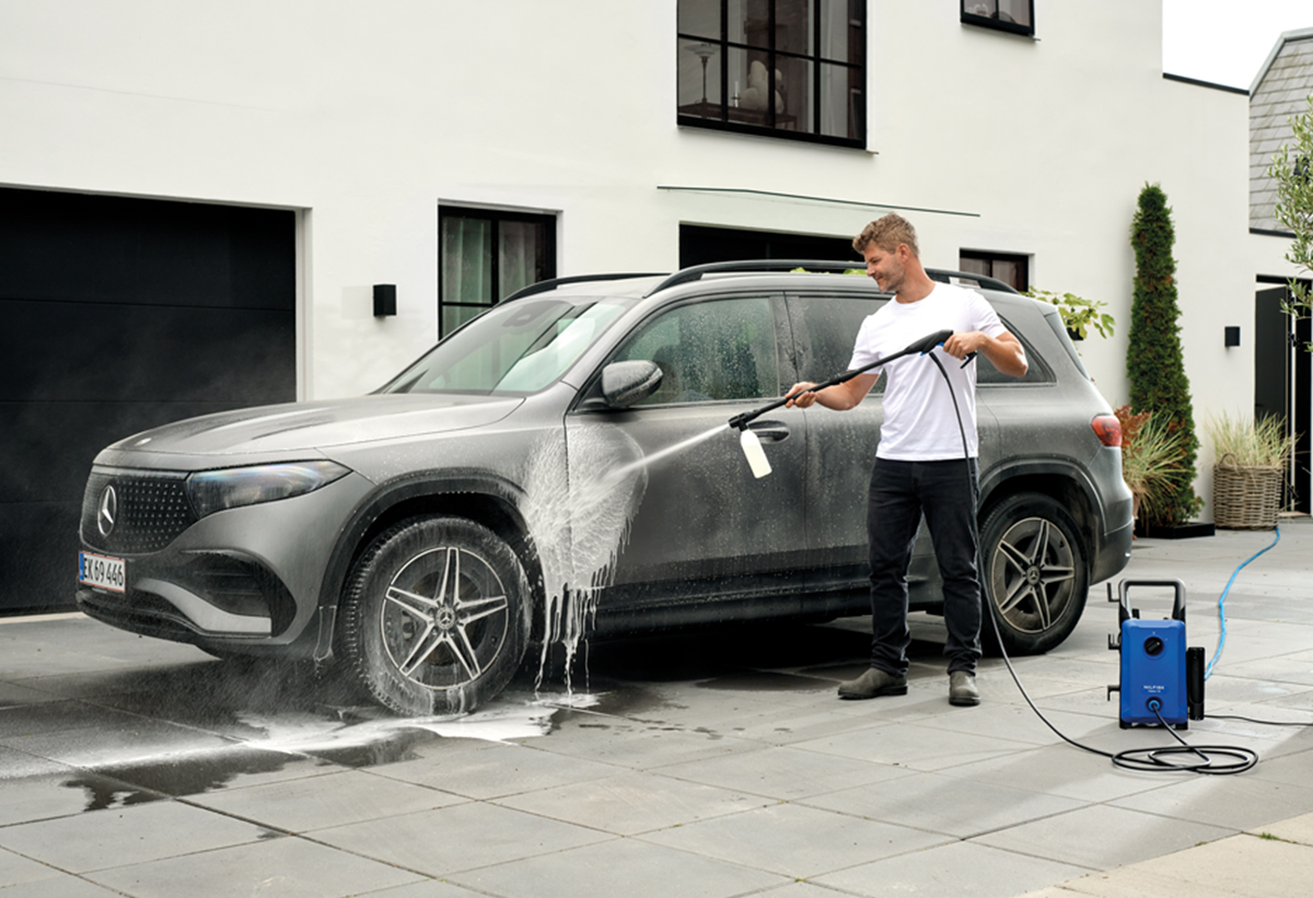 Απεικονίζεται άνδρας να χρησιμοποιεί το μηχάνημα για να πλύνει αυτοκίνητο.